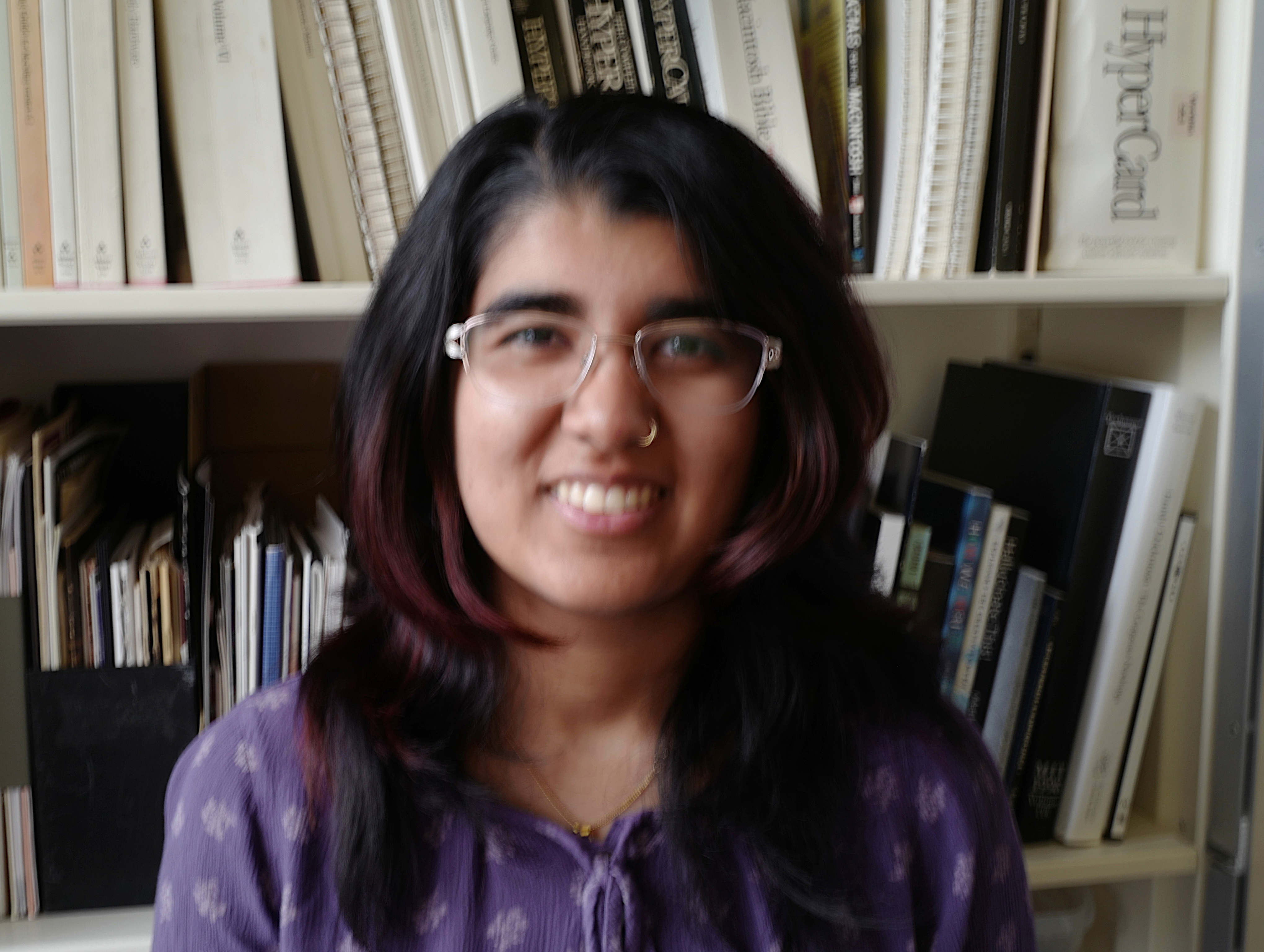Aadya is standing in front of a bookcase with software packages.