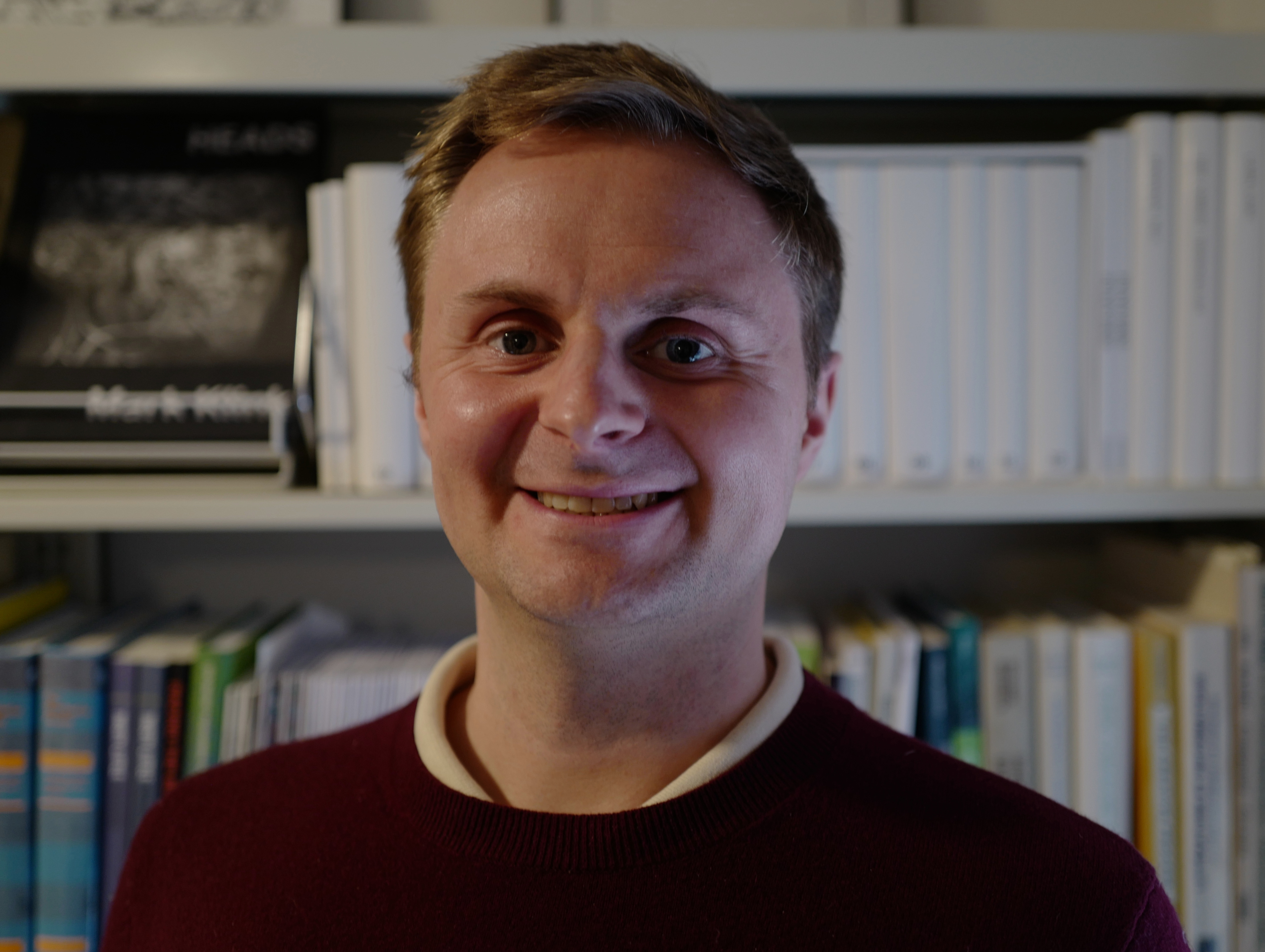 Jakob is standing in front of computer-generated books.