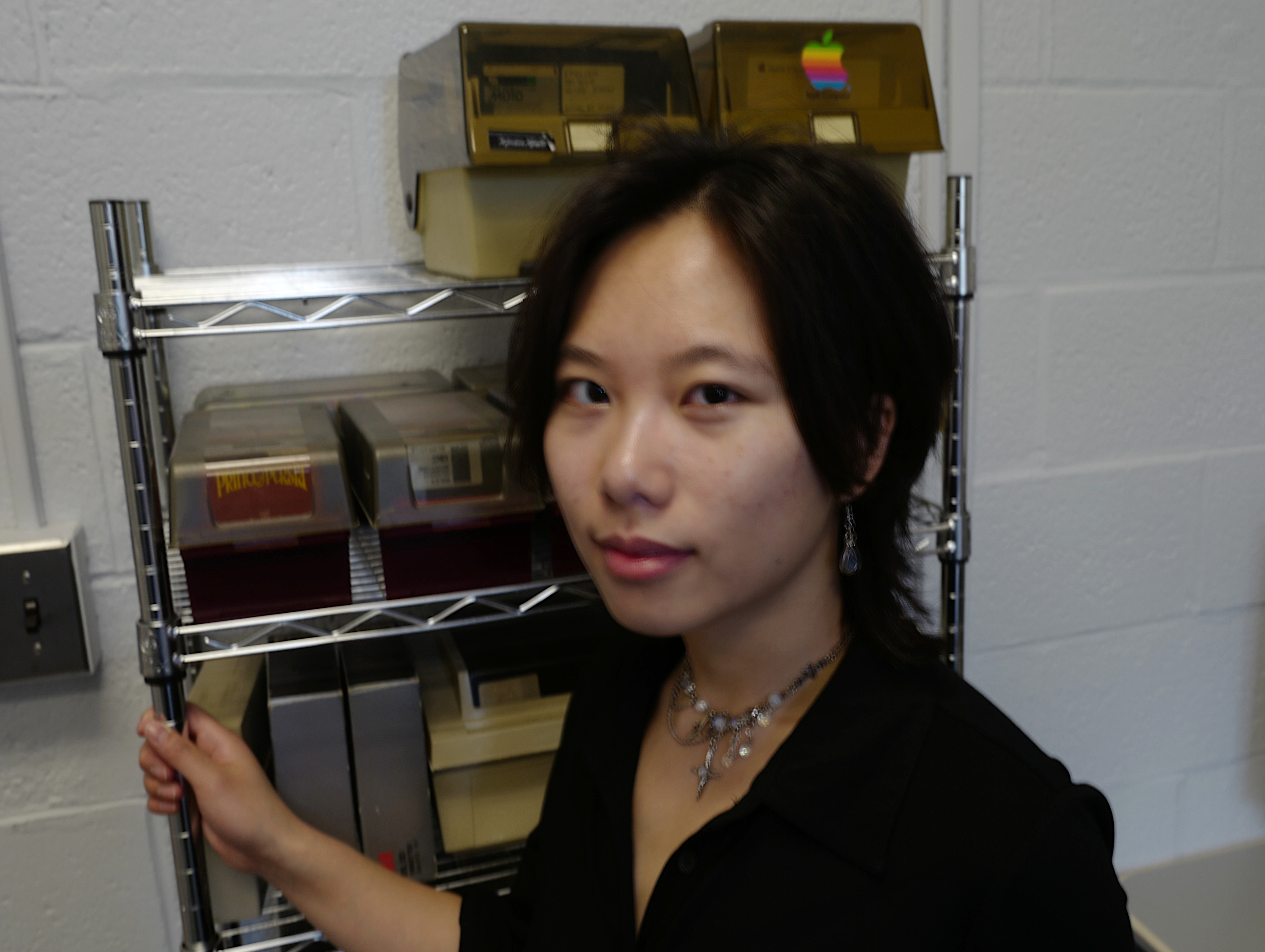 Michelle is standing in front of a rack of floppy disk containers.